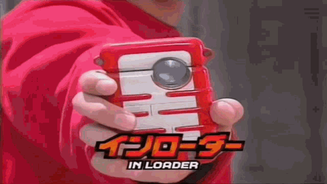 a person in a red hoodie is holding a red and white device in their hand .