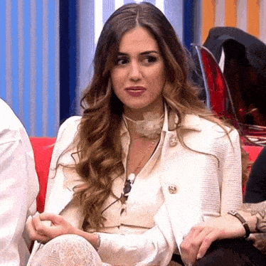 a woman in a white jacket sits on a couch