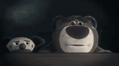 a teddy bear and a clown are sitting next to each other in a dark room