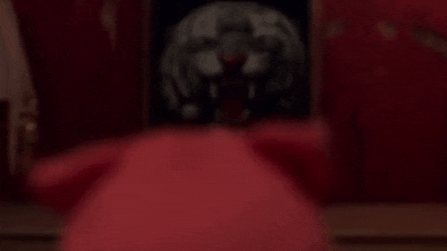 there is a picture of a lion on the wall behind a red couch .