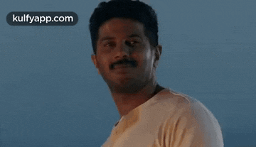 a man with a mustache is looking at the camera .
