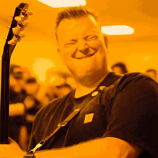 a man with his eyes closed is holding a guitar and smiling