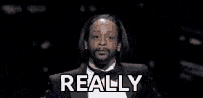 snoop dogg is wearing a tuxedo and smoking a cigarette while talking .