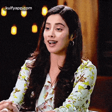 a woman in a floral shirt is sitting at a table with her mouth open .