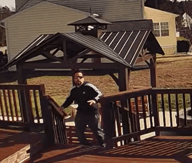 a man is standing on a deck next to a gazebo and a house .