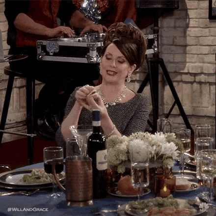 a woman is sitting at a table with a bottle of wine and glasses of wine .