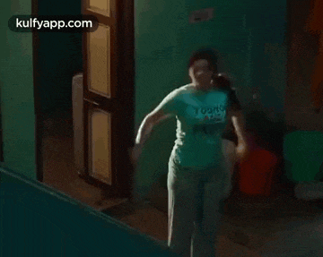 a woman in a blue shirt is standing in a room .