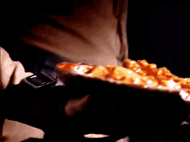 a close up of a person holding a pizza in their hand