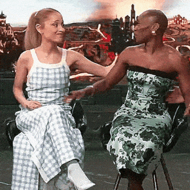 two women are sitting next to each other on a chair and talking to each other .