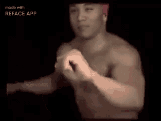 a shirtless man wearing a red headband is sitting in a dark room with his arms outstretched .