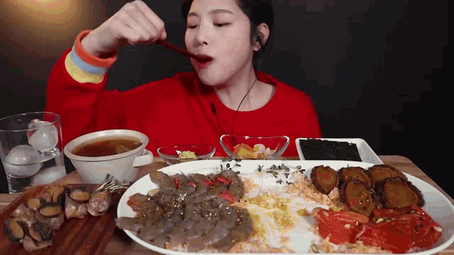 a woman in a red sweater is eating a plate of food with a spoon