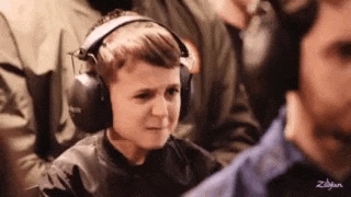 a young boy wearing headphones is making a funny face while playing a video game .