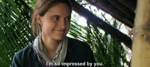 a woman is smiling and talking to another woman in a jungle .