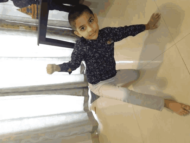 a young boy sitting on the floor with a fist in the air