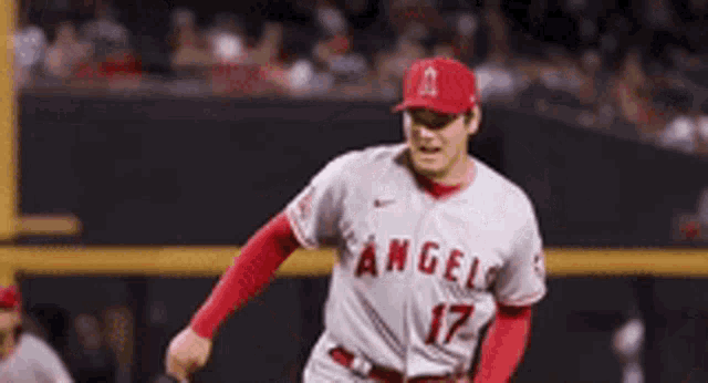 a baseball player wearing a white and red angels jersey is running on the field .