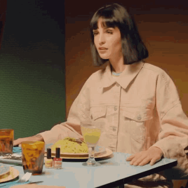 a woman in a pink jacket is sitting at a table