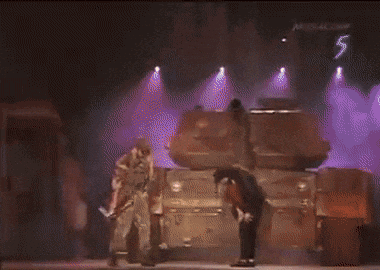 a man is holding a gun while walking on a stage in front of a crowd .