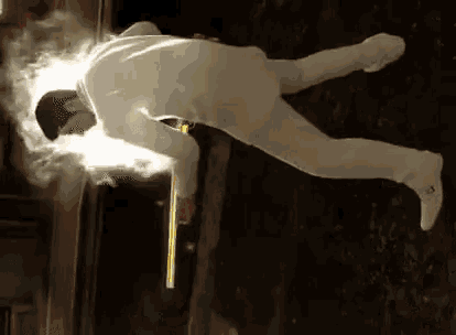 a man in a white suit is flying through the air while holding a stick .