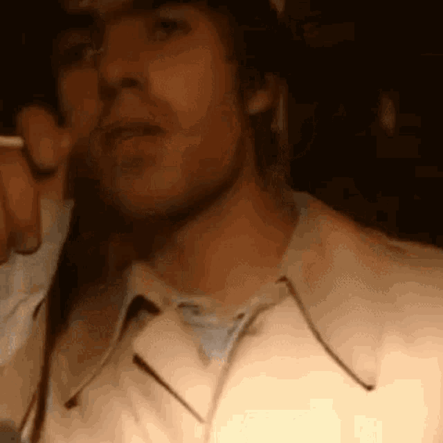 a man is smoking a cigarette in a dark room while wearing glasses .