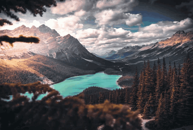 a lake surrounded by trees and mountains with a cloudy sky