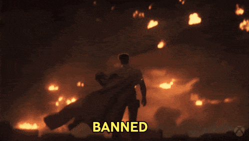 a man in a cape is standing in front of a fire and the word banned is on the bottom