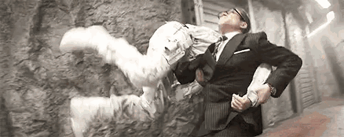 a man in a suit and tie is holding a person in his arms in a room .
