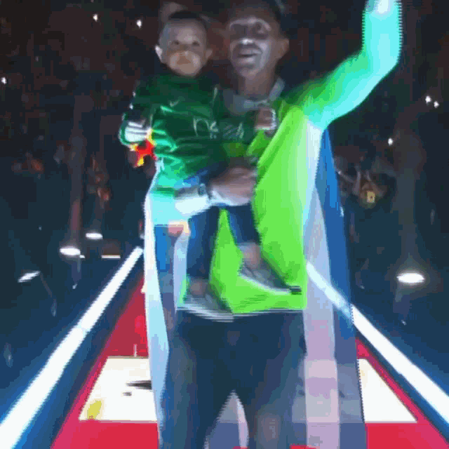 a man in a green shirt is holding a child in his arms