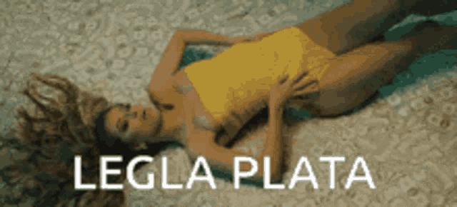 a woman in a yellow swimsuit is laying on a beach with the words legla plata written below her