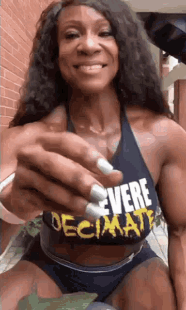 a woman with long white nails is wearing a black tank top that says `` ever decade '' .