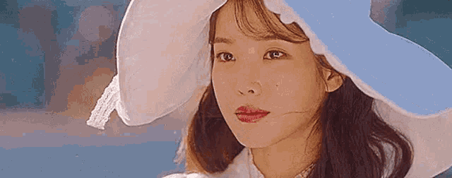 a close up of a woman wearing a hat and a white dress .