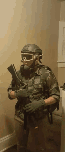 a man in a military uniform is holding a gun and wearing a helmet and goggles