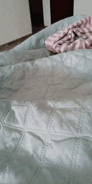a bed with a blue quilt and a pink blanket