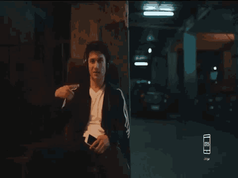 a man wearing headphones is pointing at something in a dark room