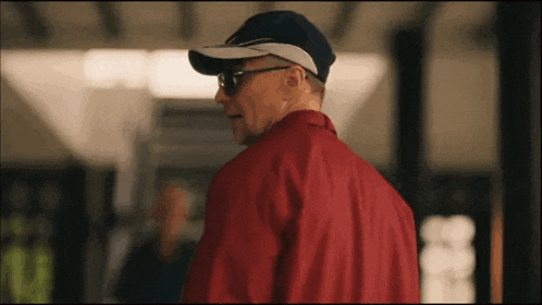 a man wearing a baseball cap and sunglasses is standing in a room .