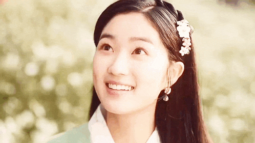 a close up of a woman wearing a flower in her hair and smiling .