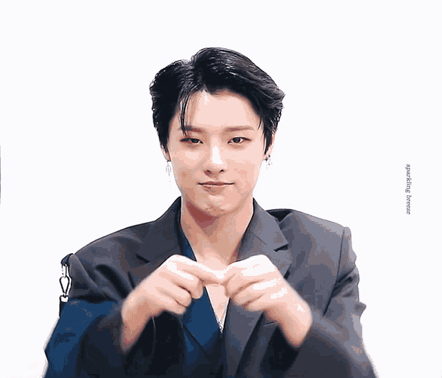 a man in a suit is making a heart sign with his hands