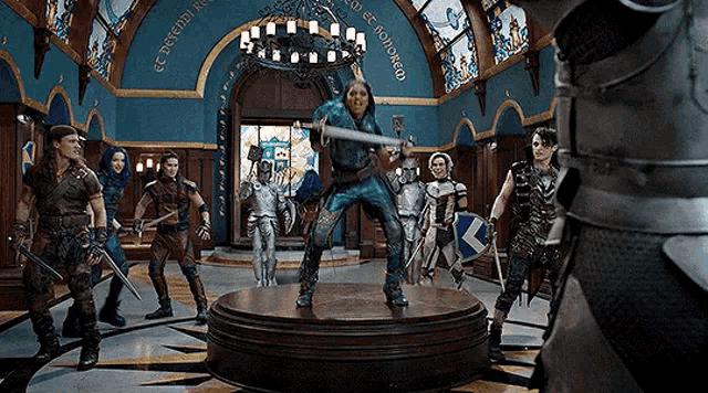 a woman is holding a sword in a room with a group of people in armor .