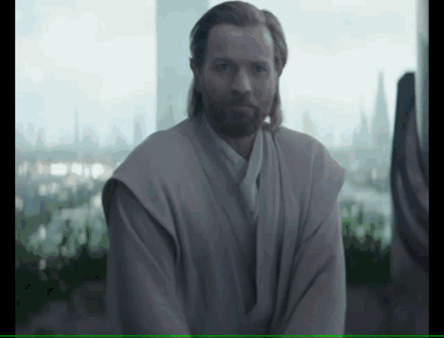 a man with a beard is standing in front of a large window