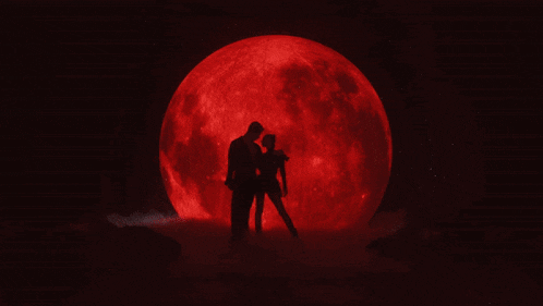 a man and a woman are standing in front of a red full moon