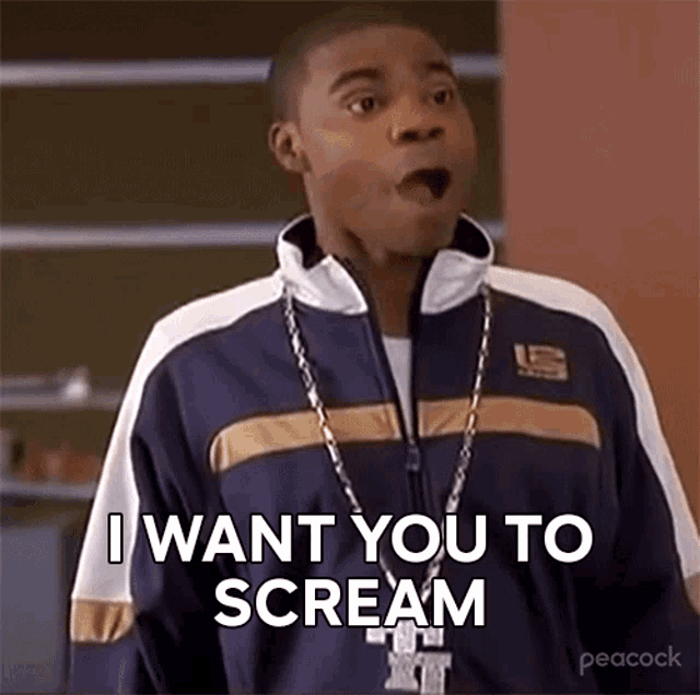 a man wearing a blue and white jacket and a necklace is saying `` i want you to scream '' .