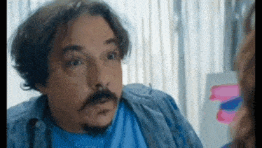 a man with a mustache and beard is looking at a woman in a mirror .