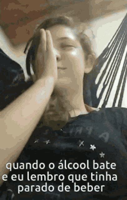 a woman is laying in a hammock covering her face with her hand and making a funny face .