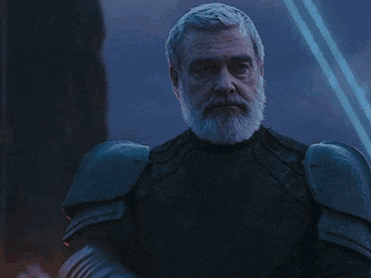 an older man with a beard is holding a red lightsaber .