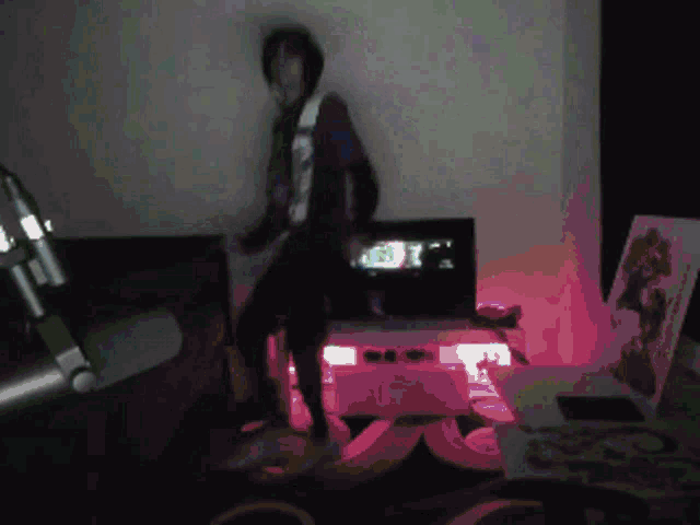 a person is dancing in a dark room with a picture of a woman on the wall