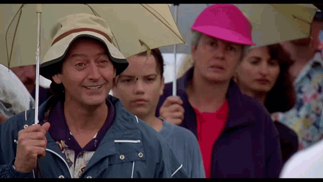 a man in a hat is holding an umbrella in a crowd