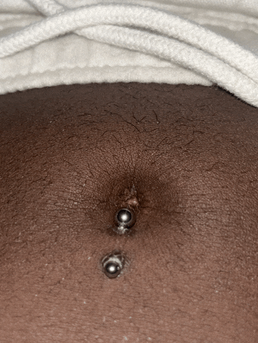 a close up of a woman 's belly with a navel piercing