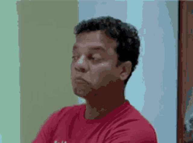a man in a red shirt is making a funny face with his eyes closed
