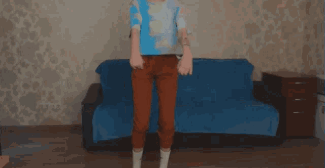 a woman is squatting in front of a couch with a blue blanket
