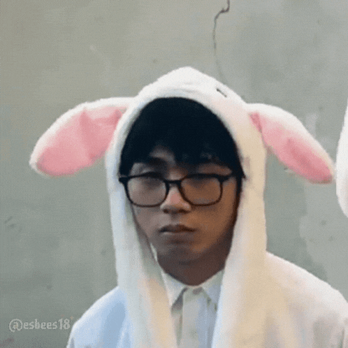 a man wearing glasses and bunny ears is making a face .