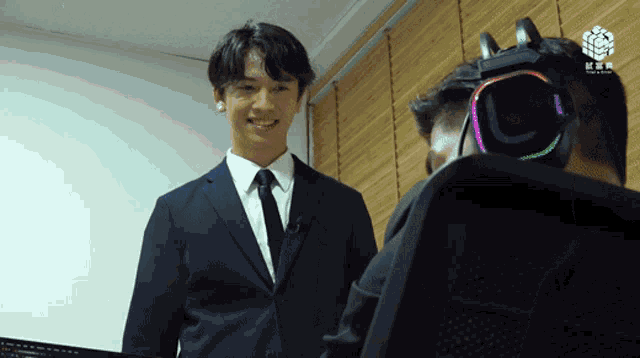 a man in a suit and tie is smiling while wearing headphones